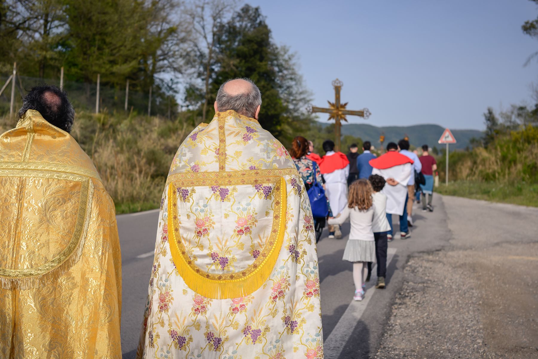 Il sacerdote in paramenti dorati segue la croce processionale