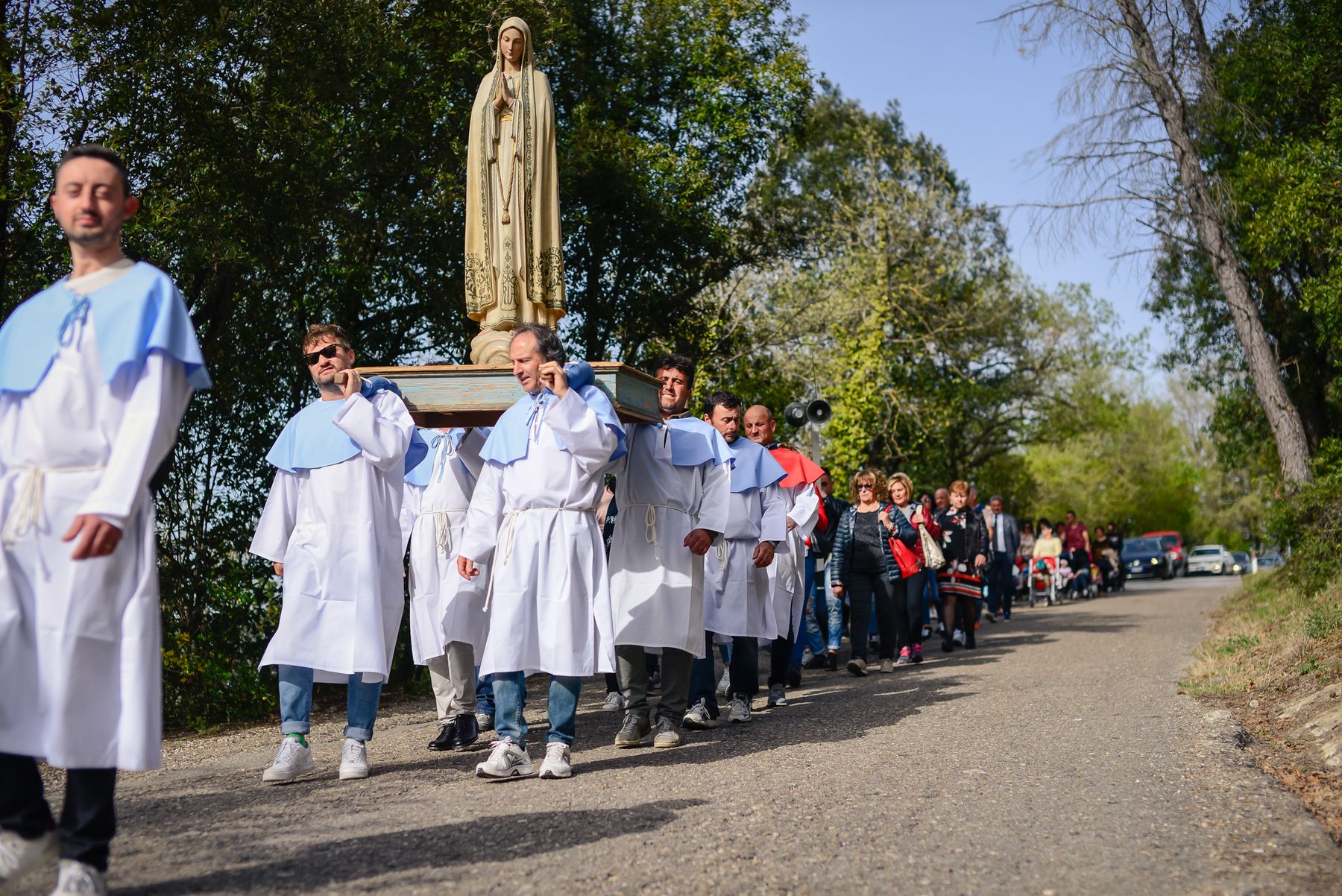 I portantini trasportano la statua della Madonna lungo la strada di campagna